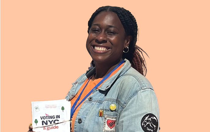 Amanda smiling while holding a flyer in front of an African American Day Parade backdrop.