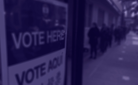 "Vote Here" sign outside of polling site is translated into Spanish to read "Vote Aqui" underneath it with a purple overlay