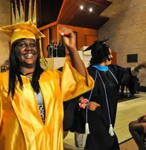 A woman smiling broadly in a bright yellow cap and gown at a College & Community Fellowship graduation ceremony.​​ 