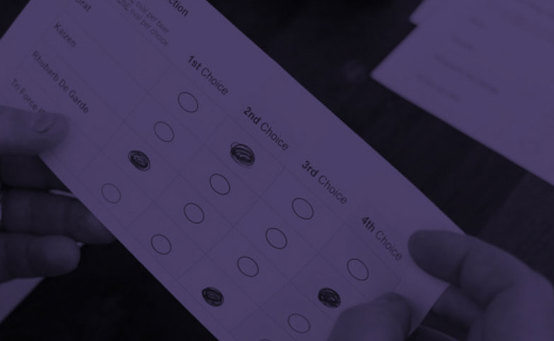 Voter filling out bubbles on their ballot with purple overlay