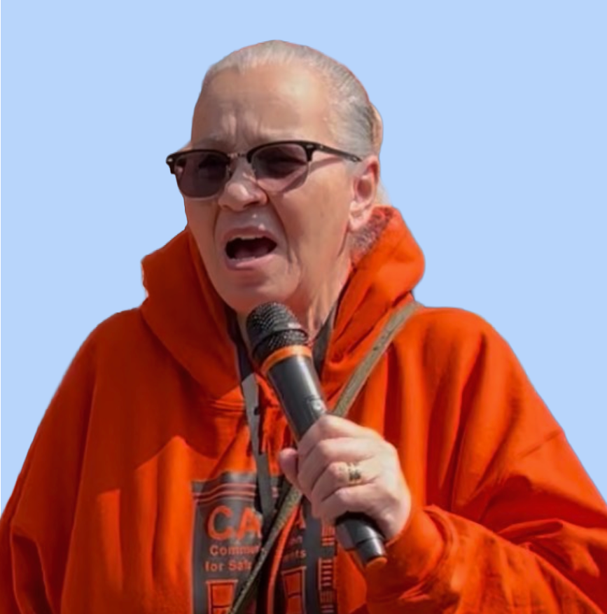 Pat Jewett speaking into a microphone at a CASA NYC event wearing an orange CASA hoodie.