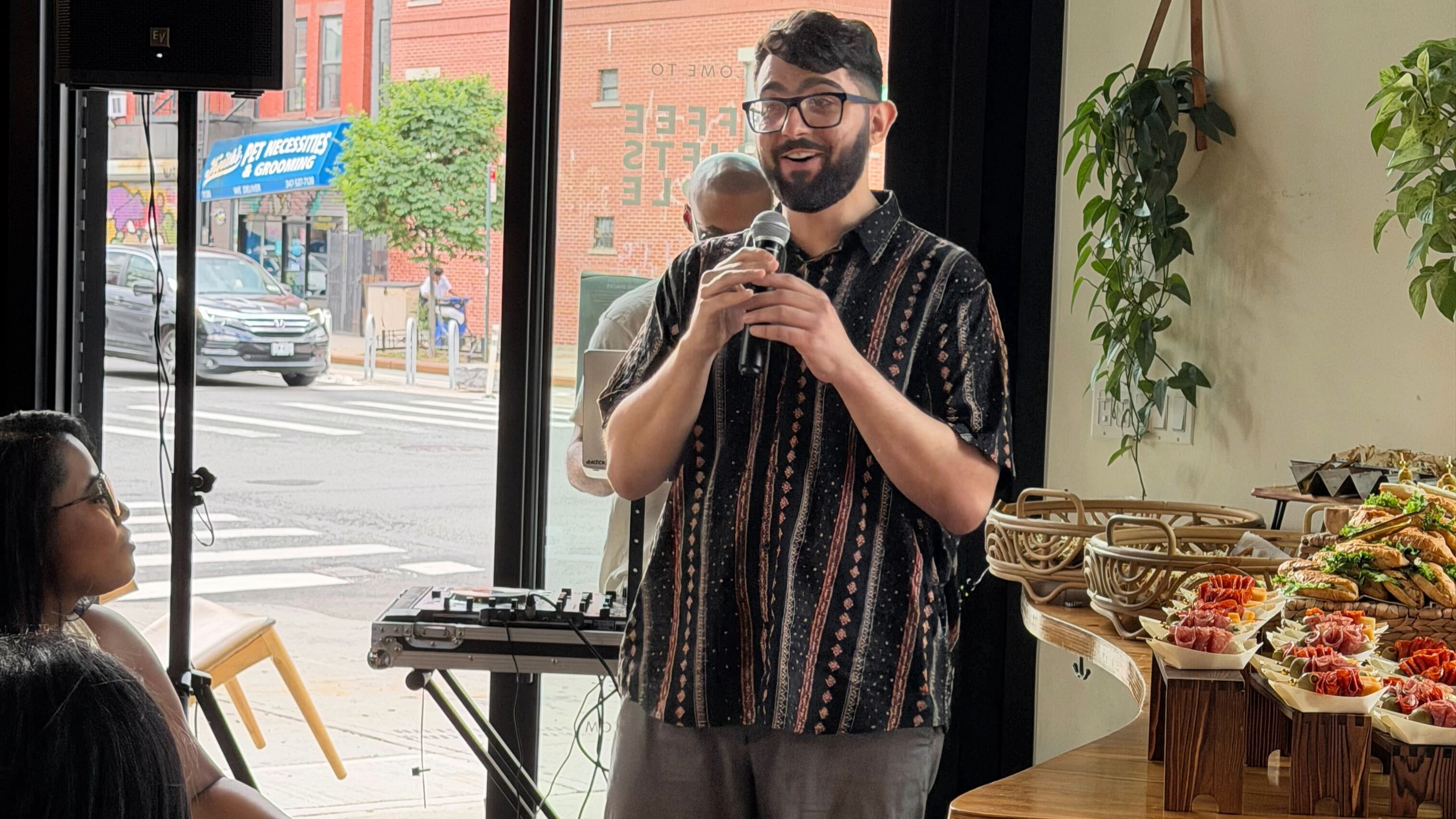 Luke holding a microphone at an event in Brooklyn's Cups Cafe