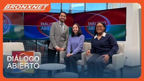 Two N Y C Votes staff members sitting in a chair next to a standing host of the Dialogo Abierto BronxNet television program