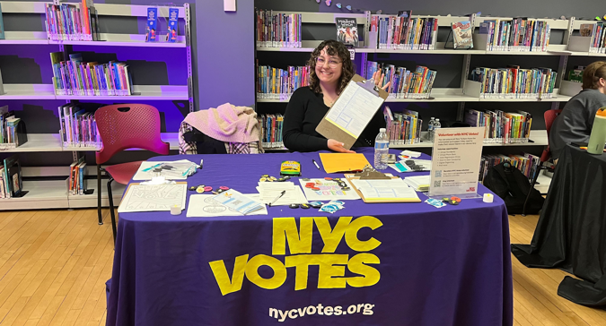 One NYC Votes Youth Ambassador sets up NYC Votes Voter Registration booth in library.