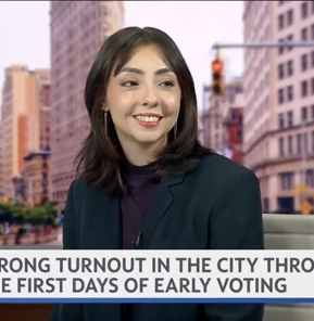 Jadel Munguia smiles while seated on a Spectrum News NY1 news set. A lower-third banner reads, “Strong turnout in the city through the first days of early voting.”
